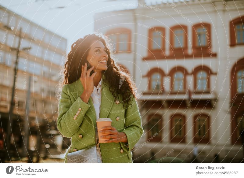 Young woman using smartphone on the street and holding takeaway coffee beautiful people beautiful woman casual cellphone cheerful city city life city street