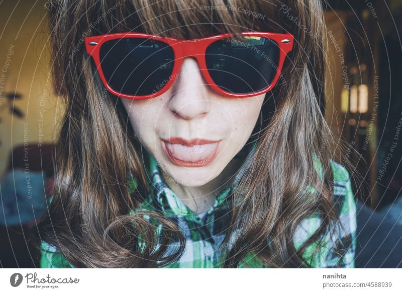 Funny portrait of a young woman wearing red sunglasses fun funny face nerd nerdy weird close headshot close up plaid freak home dreamy possitive expression