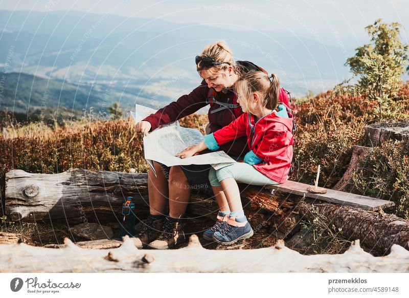 Family trip in mountains. Mother and her little daughter examining a map, sitting on stump during trip family child vacation summer hike travel journey active