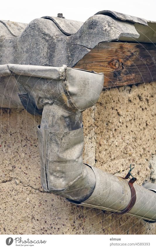 !Trash! / old, broken gutter with downpipe in front of a corrugated asbestos roof of a building / plug-in system Eaves zinc-plated Downspout Broken dilapidated