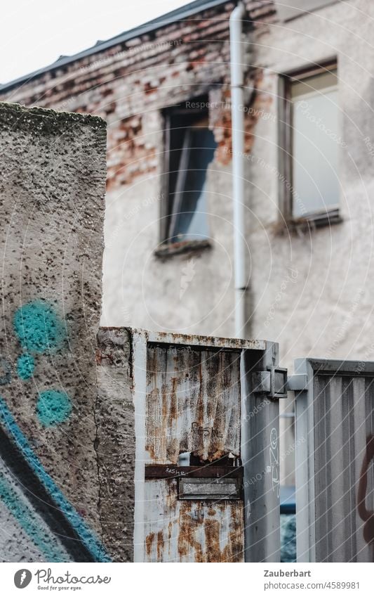 View over wall, gate and rusty mailbox to house wall with two windows and rain gutter Wall (barrier) Colour Mailbox Rust Goal Facade Shabby Window Rain gutter