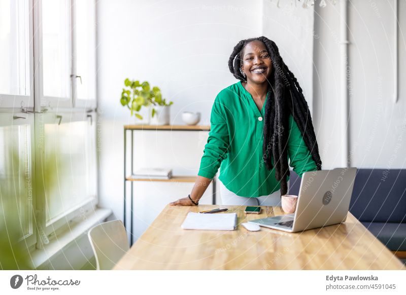 Young adult female professional working in a modern office black millennials hipster indoors loft window natural one attractive successful people confident