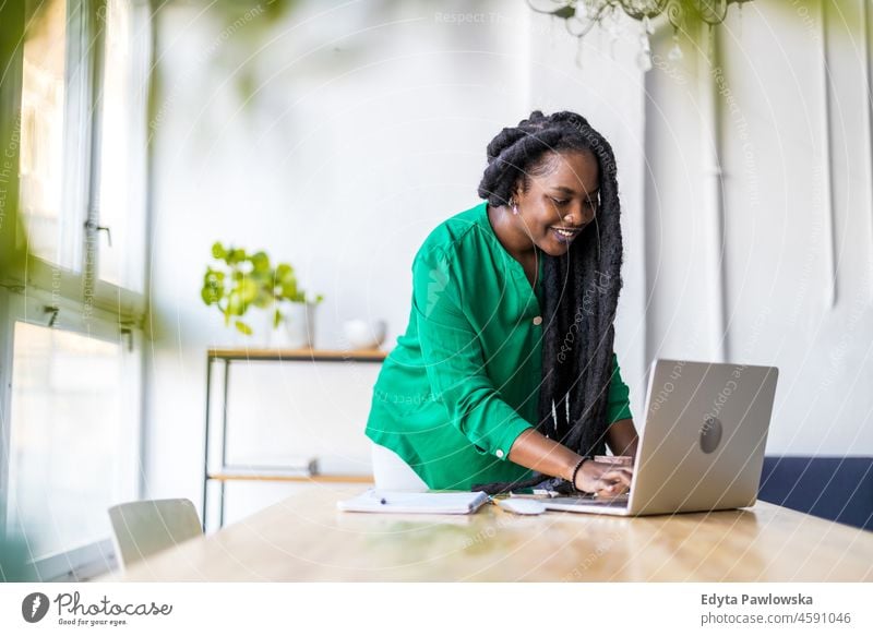 Woman working on laptop in her office black millennials hipster indoors loft window natural adult one attractive successful people confident person beautiful