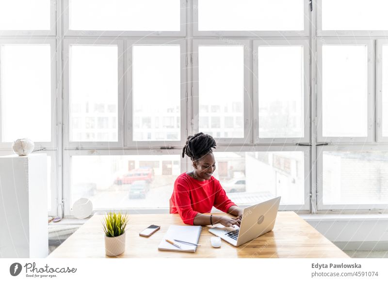 Woman working on laptop in her office black millennials hipster indoors loft window natural adult one attractive successful people confident person beautiful