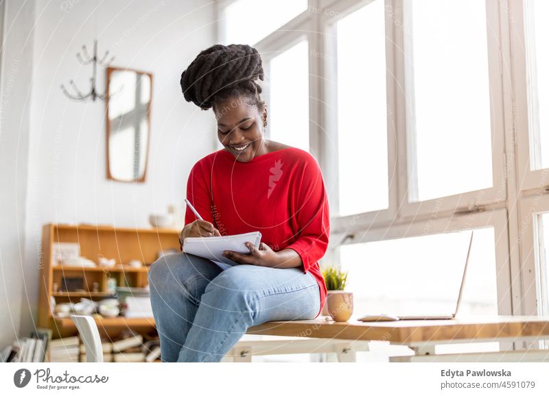 Young adult female professional working in a modern office black millennials hipster indoors loft window natural one attractive successful people confident