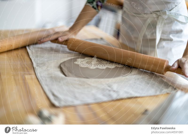 Close-up of craftswoman working on her pottery in workshop hands close up concentration patience traditional molding decorating bowl table wooden clay