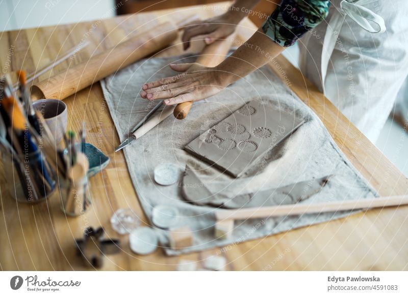 Close-up of craftswoman working on her pottery in workshop hands close up concentration patience traditional molding decorating bowl table wooden clay