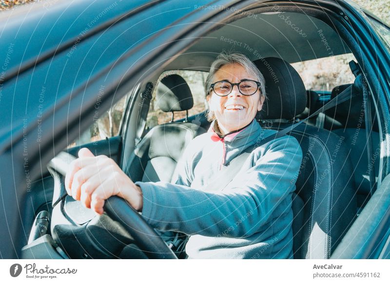 Portrait of a happy smiling senior woman learning to drive a car. Safety drive. Learning new hobby, habit and skill for this new year. Elderly person approving the driving license.