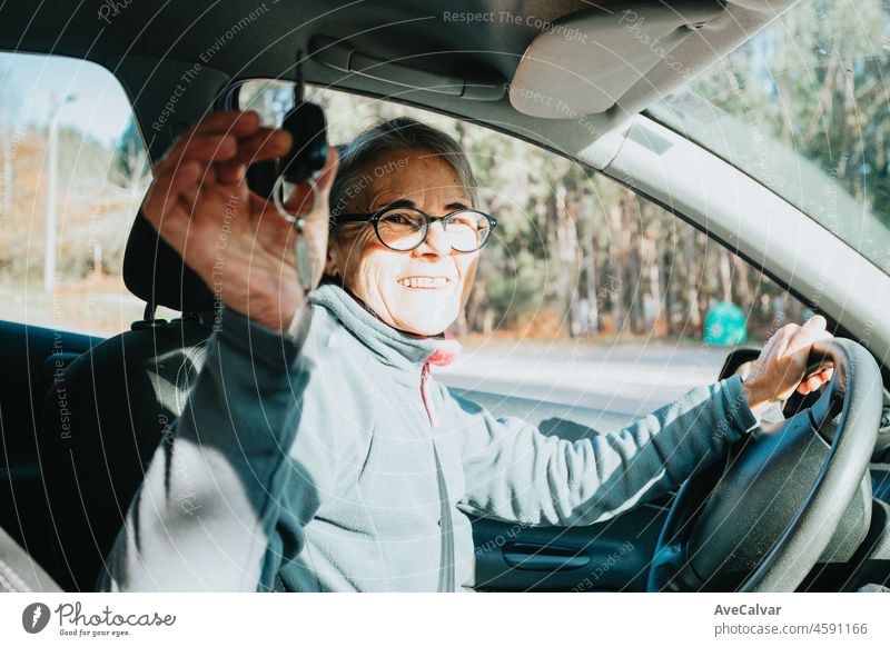 Portrait of a happy smiling senior woman learning to drive a car holding the car key to camera.Safety drive.Learning new hobby,habit and skill for this new year.Old person approving driving license