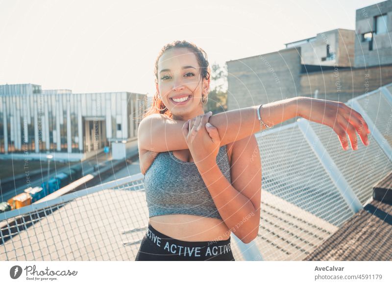 African sports woman standing stretching her arms while smiling to camera urban sport scenario. Sunset time. Beauty healthy arab woman. Sport cloths, new habits for a new year, lose weight.