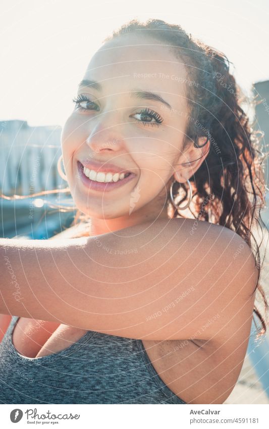 African sports woman standing stretching her arms while smiling to camera urban sport scenario. Sunset time. Beauty healthy arab woman. Sport cloths, new habits for a new year, lose weight.