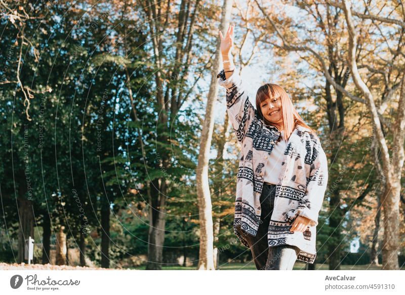 Young curvy red head woman smiling and greeting outdoors with copy space. Postal card concept. Ad and advertising. Waves her hand, greeting. female happiness