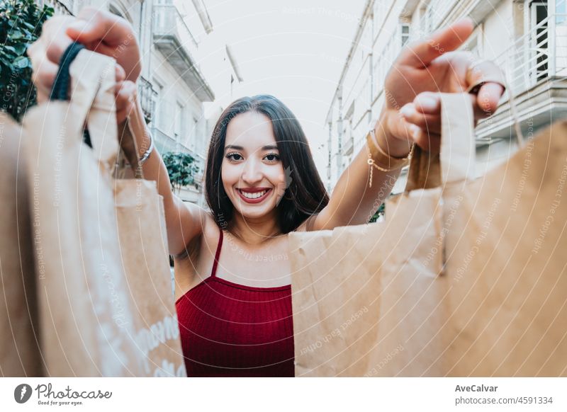 African American woman is holding a pack of a paper bags to camera while smiling to camera during a happy day. Excited about new shops. New year new life style new cloths. Trendy young style