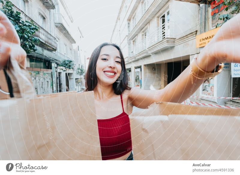 African American woman is holding a pack of a paper bags to camera while smiling to camera during a happy day. Excited about new shops. New year new life style new cloths. Trendy young style