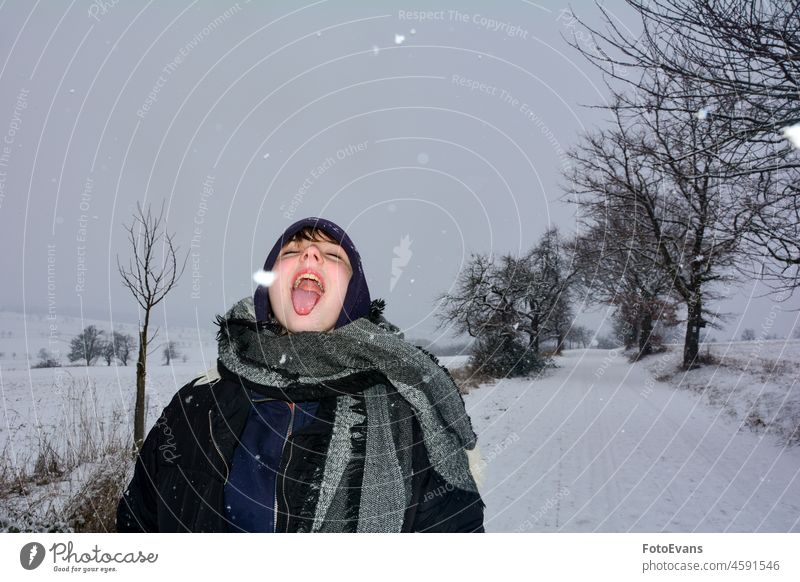 Girl in nature, catches snowflakes with her tongue fun clothing joy scarf cap mouth cold Road trees dirt road child season way woman snowy snowfall winter