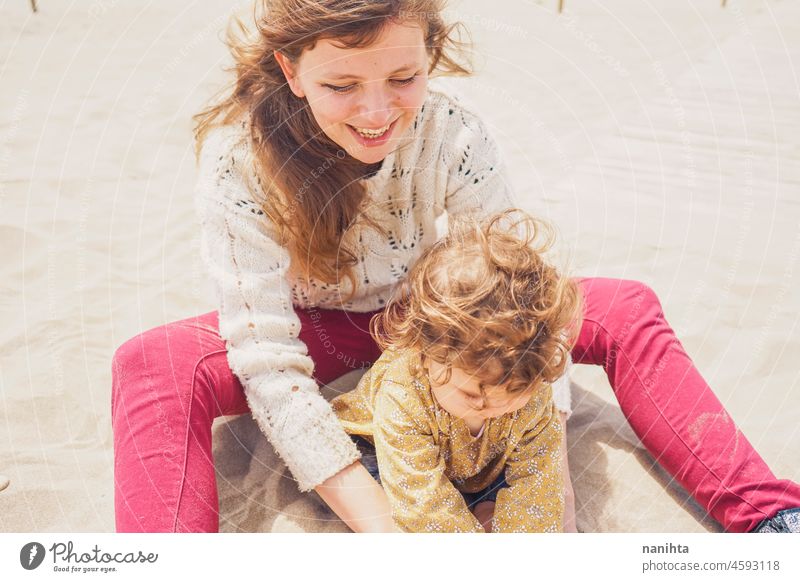 Young mom playing with her baby in the sand family motherhood vacation happiness happy playful fun funny childhood parenthood parenting casual candid life