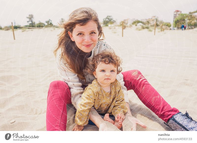 Young mom playing with her baby in the sand family motherhood vacation happiness happy playful fun funny childhood parenthood parenting casual candid life