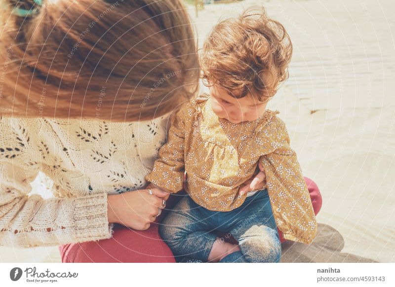 Young mom playing with her baby in the sand family motherhood vacation happiness happy playful fun funny childhood parenthood parenting casual candid life