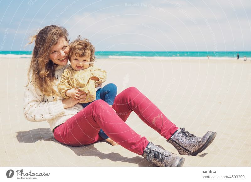 Young mom playing at the beach with her child baby family holidays single parent parenting motherhood young youth blonde playful fun funny happy happiness