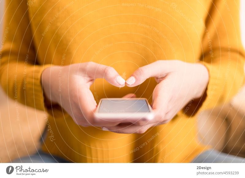 Woman in a yellow pullover, using smartphone person hand communication technology holding mobile phone lifestyle closeup screen business message touch modern