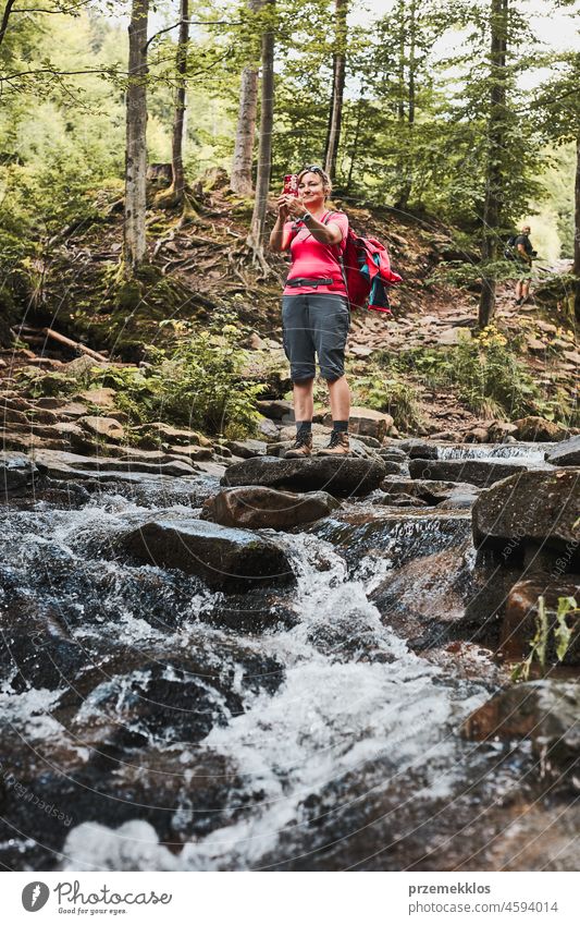 Taking pictures from vacation. Woman with backpack taking photos of landscape using smartphone camera summer trip mountain travel journey adventure hiking