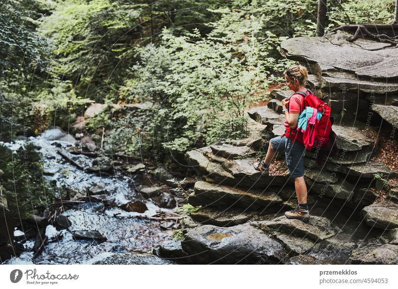 Woman with backpack hiking in mountains. Woman taking break sitting on rock adventure trip travel vacation trekking summer woman active journey wanderlust