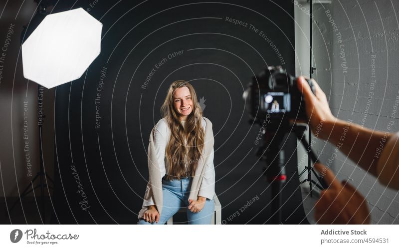 Anonymous male taking photo of female sitting on chair in professional studio woman photo camera photographer take photo equipment trendy model octabox