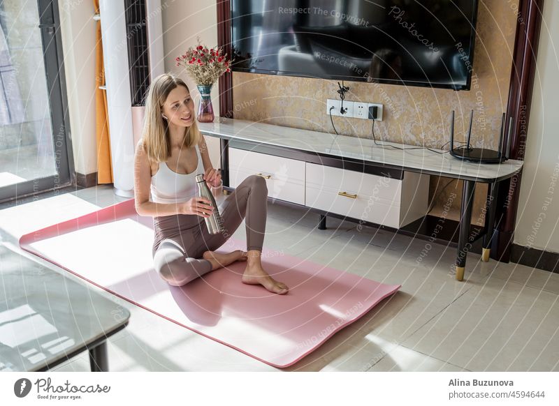 Smiling fit yoga fitness trainer, happy young sporty yoga coach teacher lying on mat at home. Home workout during Coronavirus covid-19 pandemic quarantine