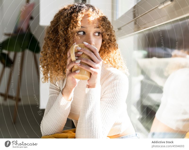 Black woman sitting on windowsill with cup and blanket drink beverage cozy comfort plaid rest relax tea female mug hot drink chill ethnic lady lounge black