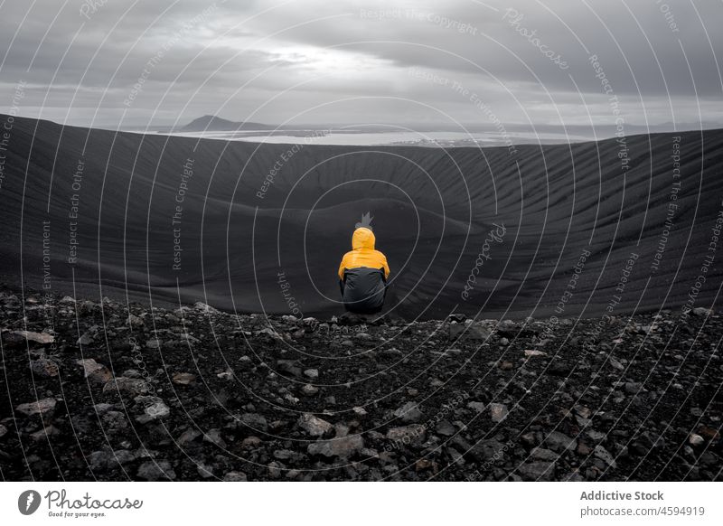 Traveler sitting in black cone shaped crater of extinct volcano tourist admire contemplate volcanic explore highland freedom altitude north adventure geology