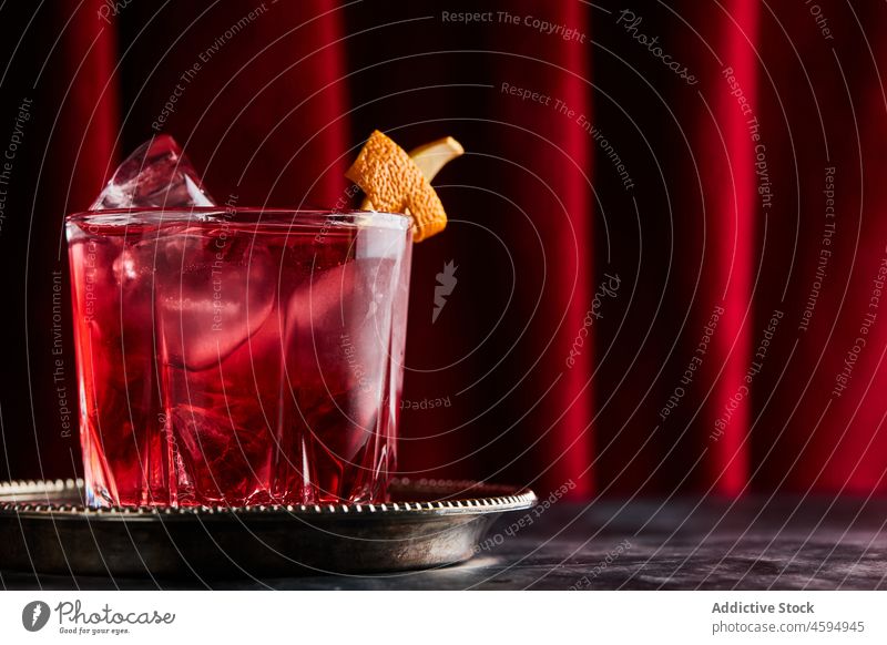 Glass of classic Negroni cocktail on marble table negroni alcohol refreshment drink beverage sofa bitter blend gin vermouth ice mix orange peel garnish citrus