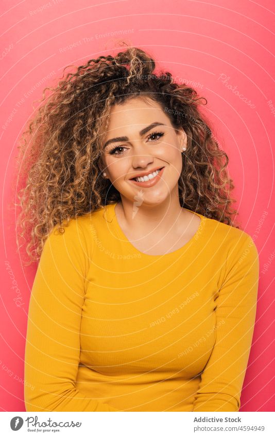 Smiling woman with curly hair in studio smile cheerful happy positive optimist young appearance casual style glad bright joy portrait colorful toothy smile