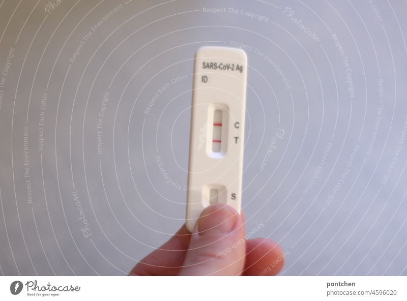 one hand holding up a positive antigen rapid test, self-test for Corona, Covid-19. Sick, infected, contagion corona Quick test Infection