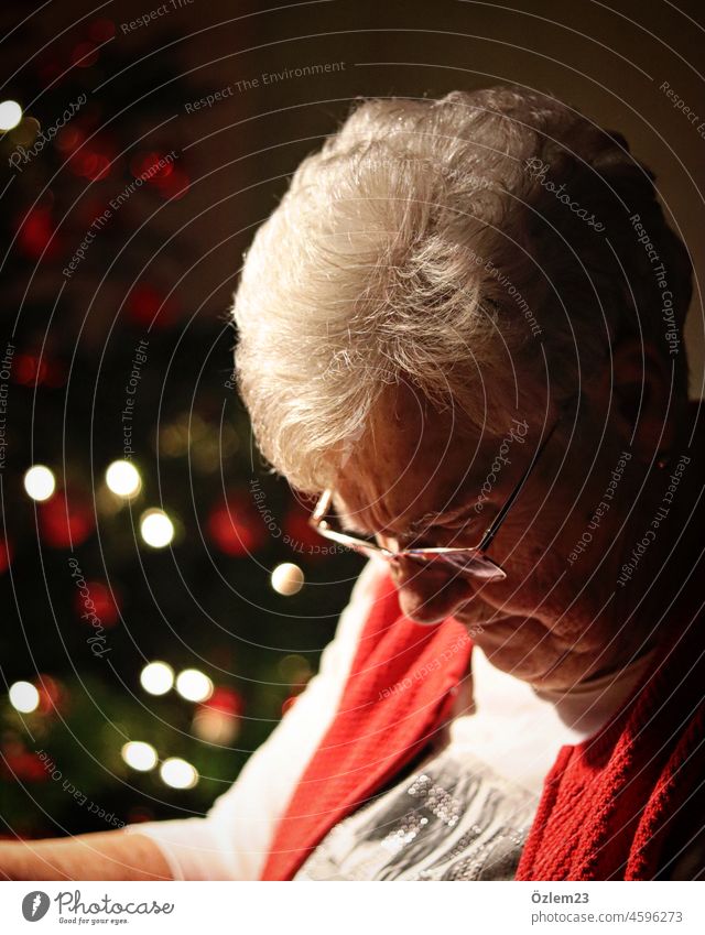 Mom-in-law sits at the dining table, next to the Christmas tree, looking down Mother-in-law grandma Great-Grandma Great grandmother Grandmother Looking Downward