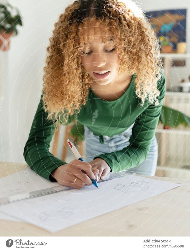 Ethnic woman drawing with pen and ruler on paper designer sketch concentrate process creative work professional occupation studio job art workshop project table