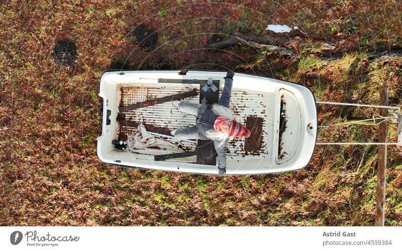 Luftaufnahme mit einer Drohne von einer lachenden Frau die in einem Boot auf Land sitzt luftaufnahme drohnenfoto frau boot sitzen land trockenem lustig spaß