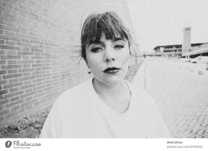 Closeup of a pretty young female with a serious look and a white shirt. Black and white. Life style mental health anxiety and sarcasm concepts. Fashion concept.