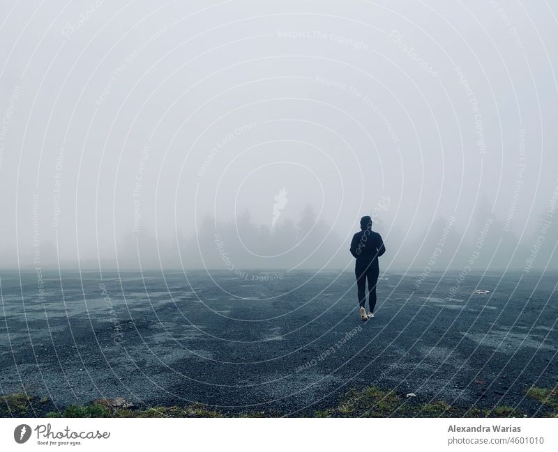 Dark or black dressed hiker in the fog at the edge of the forest Fog Wall of fog Cloud forest Misty atmosphere foggy Shroud of fog Sea of fog Covering of fog