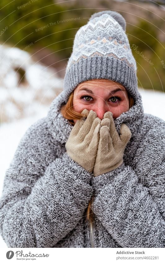 Freezing woman wearing warm clothes in winter nature woods cover mouth fun glove wintertime snow knitted excited frost outerwear frozen hat jacket cold snowfall