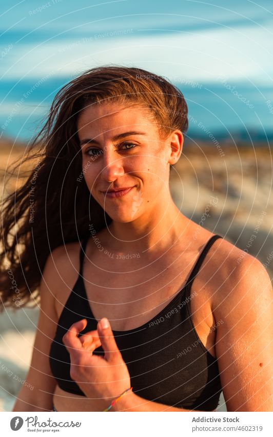 Young positive female with wet hair on seashore woman cheerful nature coastline human face summer portrait smile model appearance charming confident gorgeous