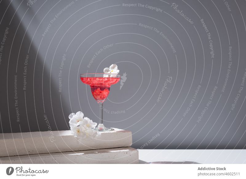 Glass of pomegranate margarita with flower blooms cocktail glass portion alcohol slice aperitif composition block glassware fresh transparent beverage drink