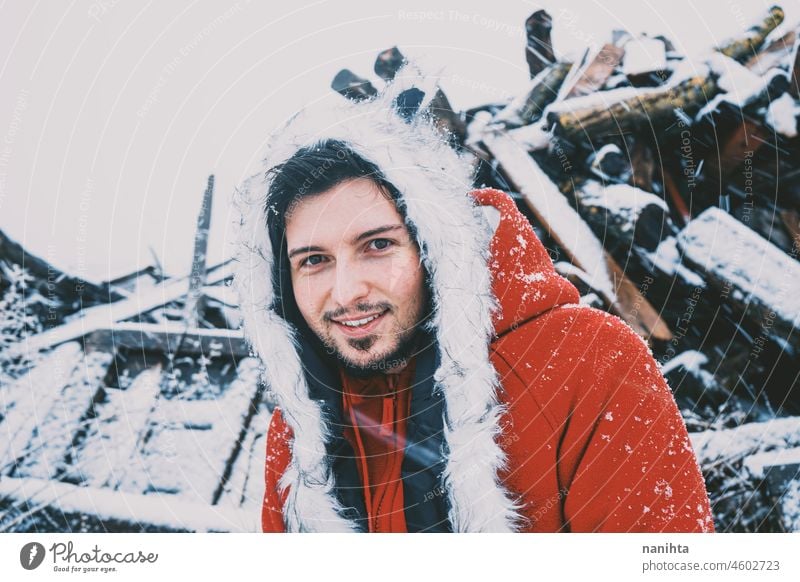 Young man enjoying a snowy day wearing a fur hat and a red hoodie winter fun funny cold freeze frozen life lifestyle white caucasian beard attractive cool fresh