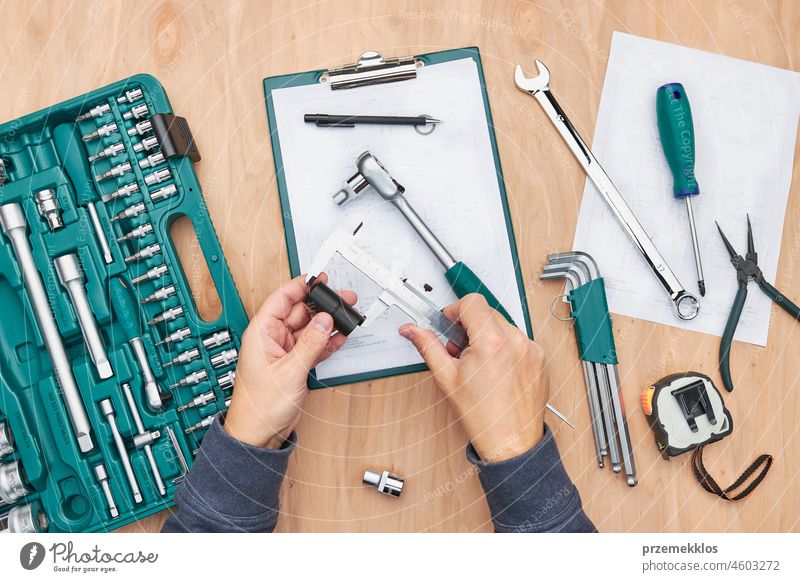 Man working in workshop using many tools. Wrench, spanner, calliper and ratchet with many attachments. Professional equipment repair engineering mechanic