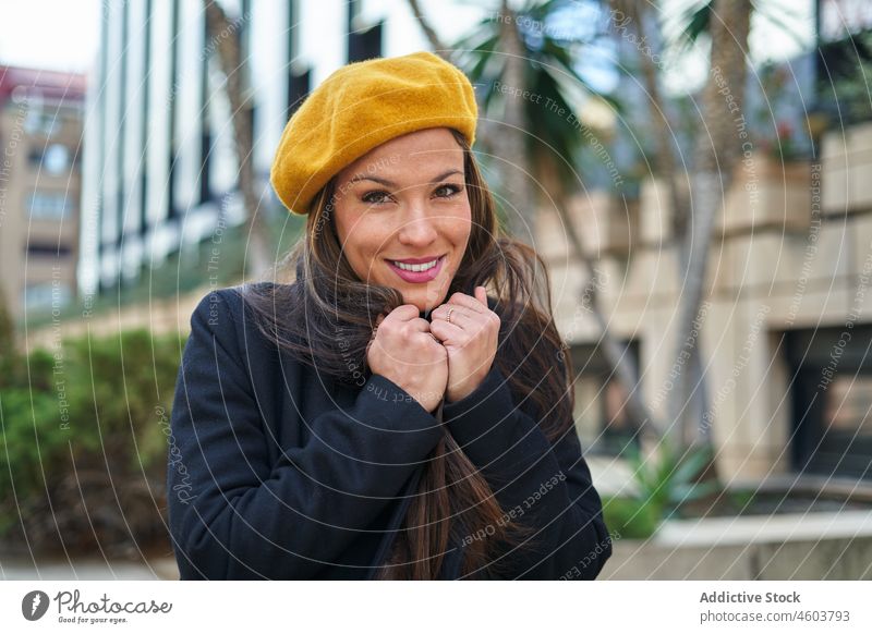 Content woman in coat feeling cold on street entrepreneur city style portrait feminine fashion urban freezing female respectable elegant positive smile attire