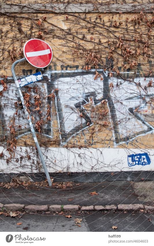 Flattened one-way street sign in front of a house wall flattened No through road Deformation Bruised Scrap metal Broken Destruction Transience Derelict Metal