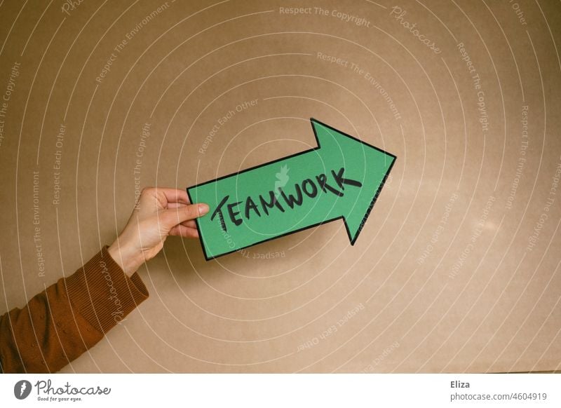 Woman holding a green arrow with teamwork written on it Teamwork Arrow Group work at the same time Working environment in common Team spirit Green authored