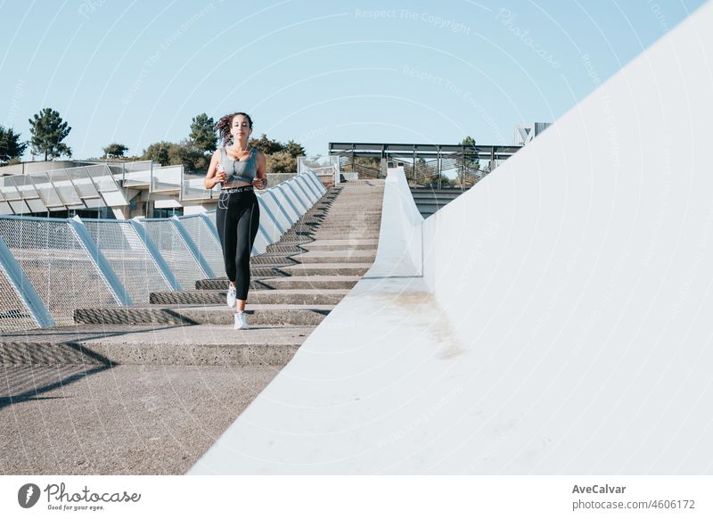 Young woman running to lose weight after starting new habits and activities. Copy space, woman listening music while training in an urban city place. Leggins and top sport cloth, healthy life concept