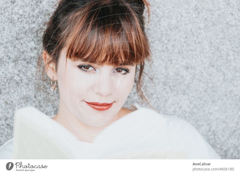 Close up portrait of a young red head girl laughing and smiling to camera while resting against a wall. Happy about hearing a joke and thinking about his future. Social network style with copy space