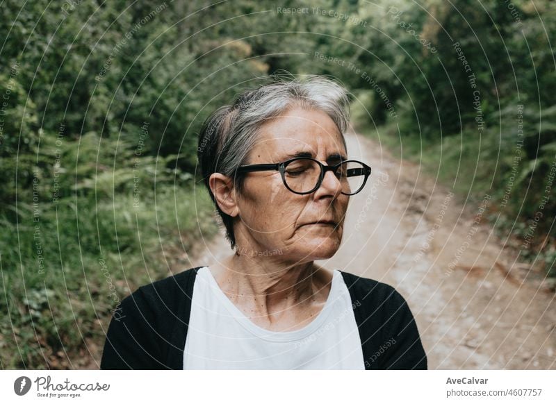 Happy senior woman serious thinking while closing her eyes. Retirement mental health resting, senior people psychology habits, doing activities. Serious and relaxing outdoors