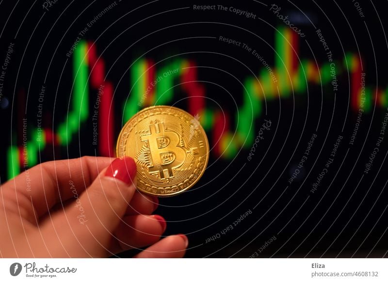 Woman holding a bitcoin coin. In the background are trading candles on a screen. Cryptocurrencies. bit coin Cryptocurrency price crypt Money trade